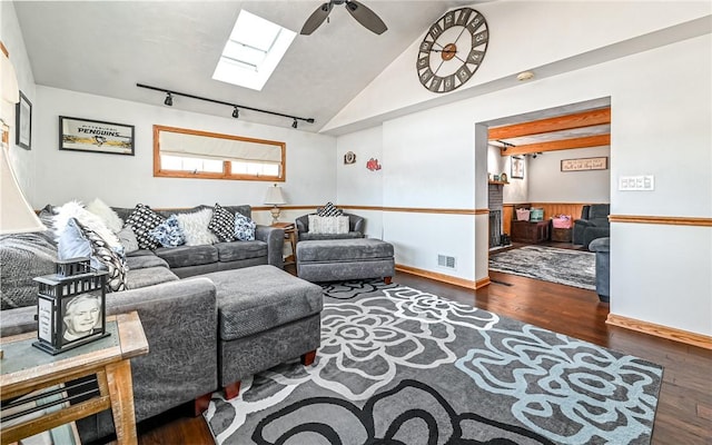 living room featuring dark hardwood / wood-style flooring, rail lighting, ceiling fan, and vaulted ceiling with skylight