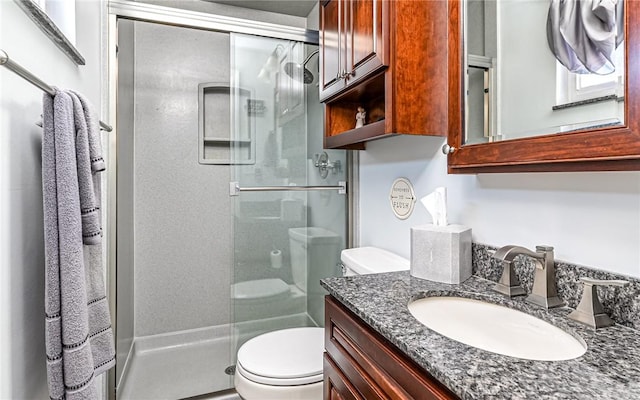 bathroom featuring vanity, toilet, and a shower with shower door