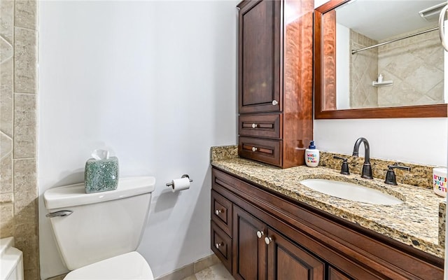 bathroom with tiled shower, vanity, and toilet