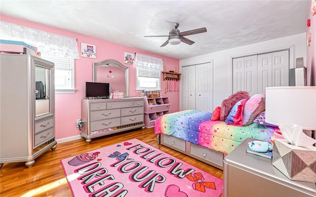 bedroom featuring ceiling fan, two closets, and light wood-type flooring