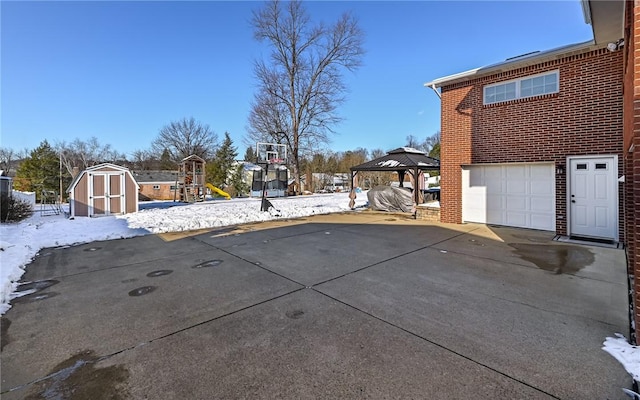 snowy yard with a gazebo, a playground, and a garage