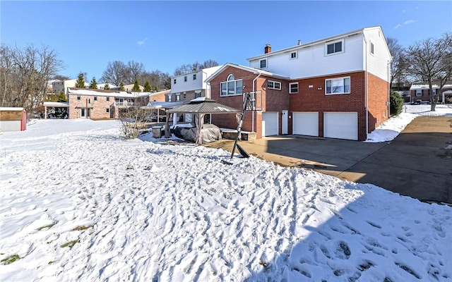 snow covered rear of property with a gazebo and a garage