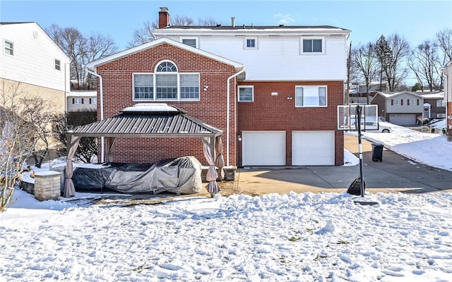 snow covered back of property with a garage