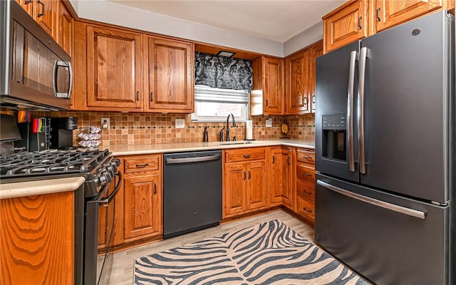 kitchen with decorative backsplash, sink, black appliances, and light wood-type flooring