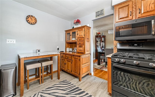 kitchen featuring black range with gas stovetop and light hardwood / wood-style floors