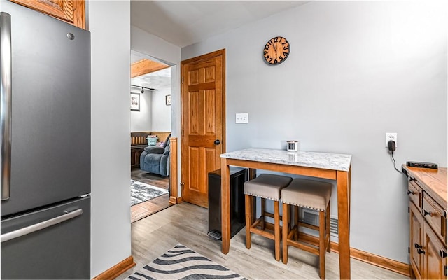 interior space with a breakfast bar area, stainless steel refrigerator, and light hardwood / wood-style floors