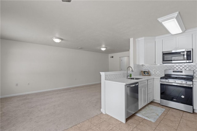 kitchen featuring white cabinets, sink, appliances with stainless steel finishes, light colored carpet, and kitchen peninsula