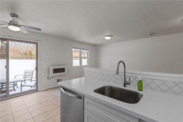 kitchen featuring sink, stainless steel dishwasher, ceiling fan, light stone countertops, and light tile patterned floors