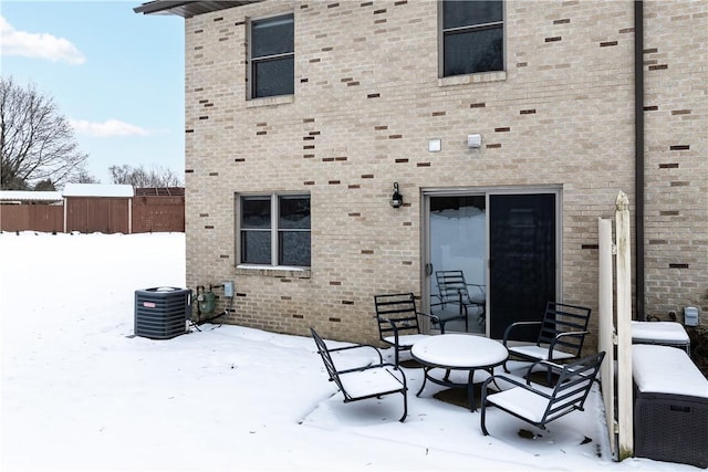 snow covered rear of property featuring central AC