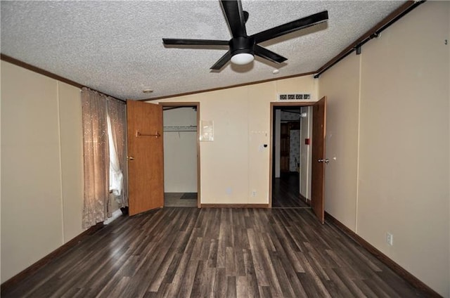 unfurnished bedroom with ceiling fan, dark wood-type flooring, crown molding, vaulted ceiling, and a textured ceiling