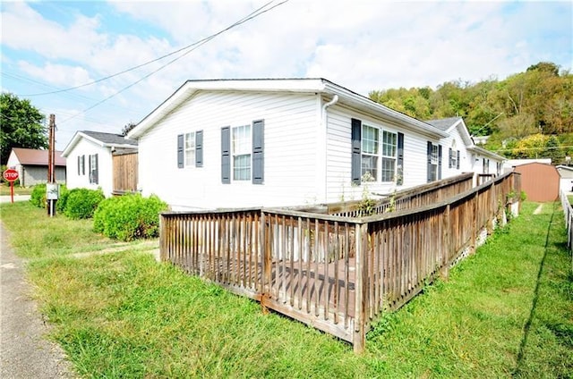 view of side of property featuring a wooden deck and a lawn