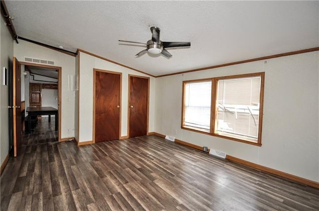 unfurnished bedroom featuring lofted ceiling, ceiling fan, ornamental molding, dark hardwood / wood-style flooring, and multiple closets