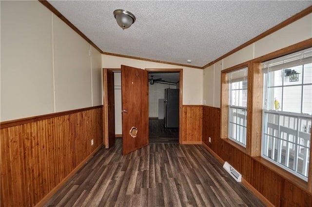 empty room with vaulted ceiling, crown molding, dark hardwood / wood-style flooring, and a textured ceiling