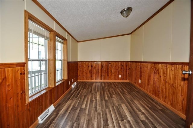 unfurnished room featuring a textured ceiling, crown molding, and dark wood-type flooring