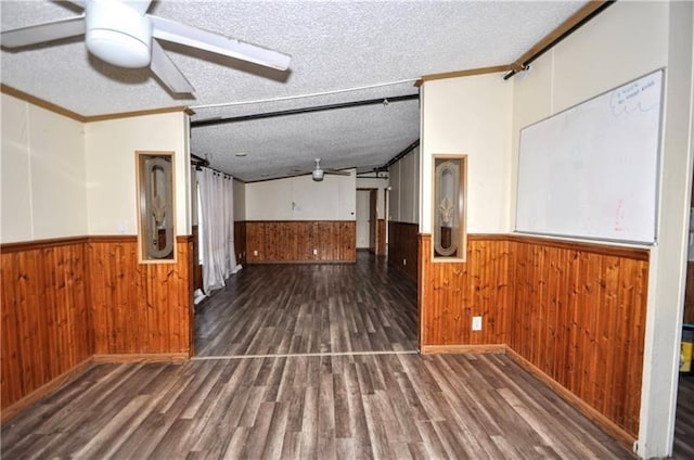 interior space featuring dark hardwood / wood-style flooring, crown molding, a textured ceiling, and wooden walls