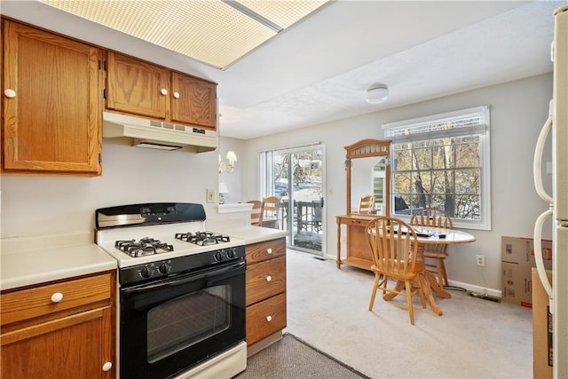 kitchen featuring gas stove, light carpet, and white fridge