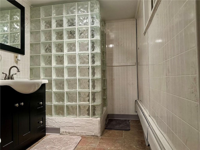 bathroom featuring walk in shower, baseboard heating, tile patterned flooring, vanity, and tile walls