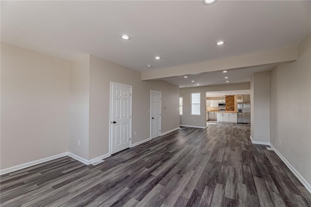 unfurnished living room with beamed ceiling and dark hardwood / wood-style floors