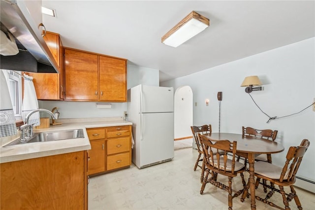 kitchen featuring white refrigerator, baseboard heating, sink, and extractor fan