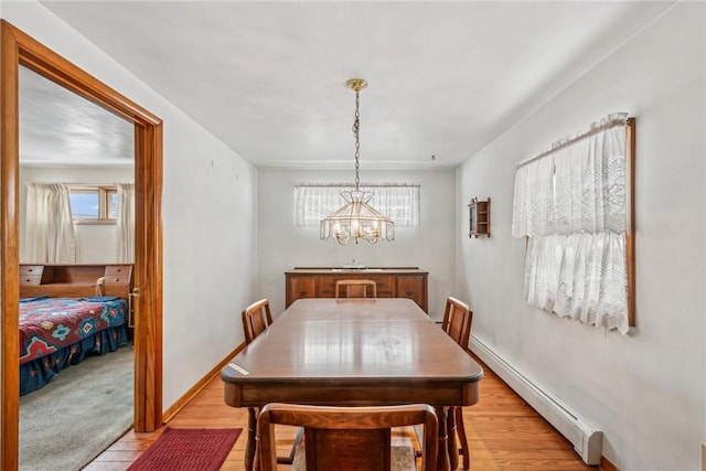 dining space with light hardwood / wood-style floors, a notable chandelier, and a baseboard heating unit