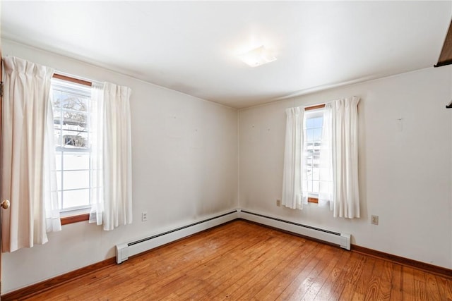 empty room featuring a baseboard heating unit and light hardwood / wood-style flooring