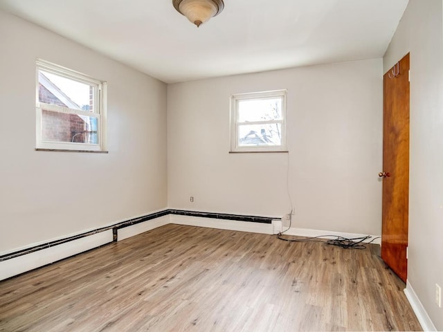 spare room with light hardwood / wood-style floors, a baseboard radiator, and a healthy amount of sunlight