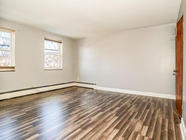 unfurnished room featuring a healthy amount of sunlight, a baseboard heating unit, and dark wood-type flooring