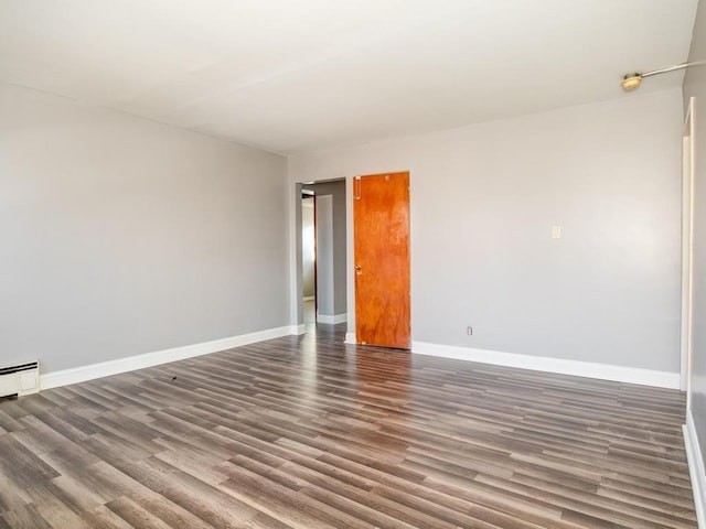 empty room with dark hardwood / wood-style flooring and a baseboard radiator