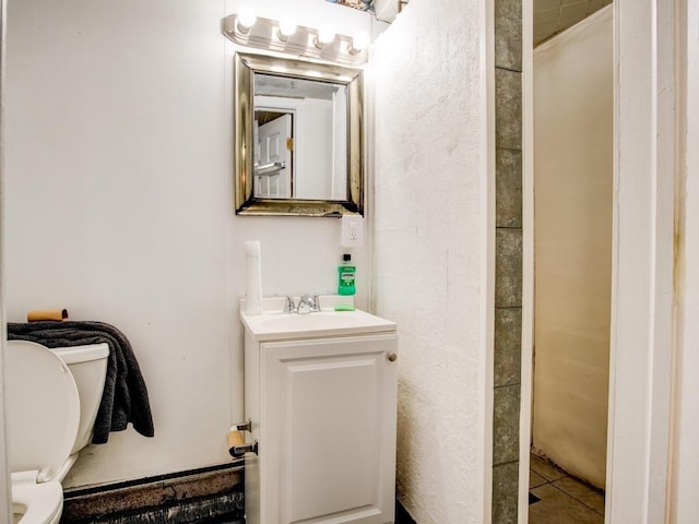 bathroom with tile patterned flooring, vanity, and toilet