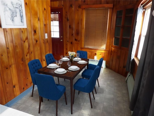 dining room with a baseboard radiator and wooden walls