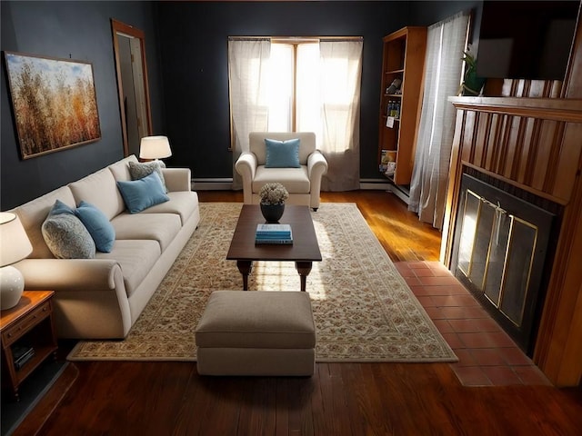 living room with hardwood / wood-style flooring, a tile fireplace, and a baseboard heating unit