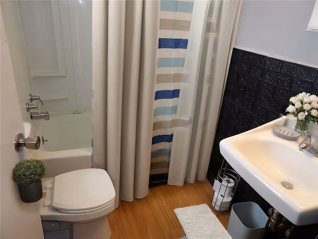 full bathroom featuring hardwood / wood-style flooring, shower / bath combination with curtain, toilet, and sink