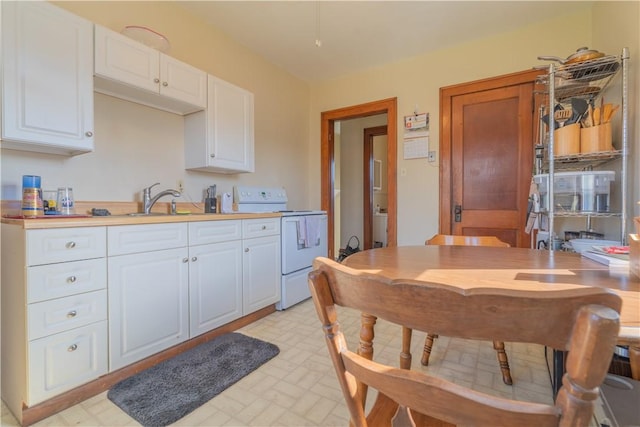 kitchen with white cabinetry, electric range, and sink