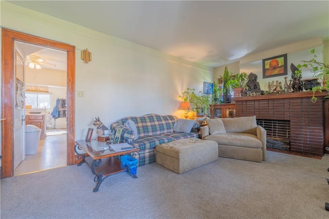 carpeted living room featuring ceiling fan, crown molding, and a brick fireplace