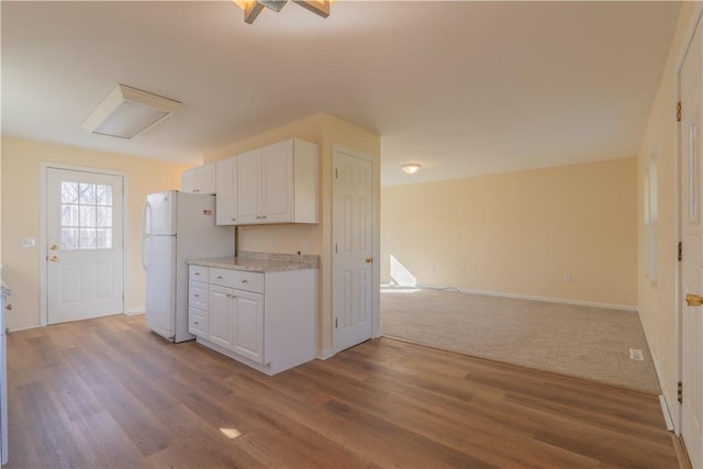 kitchen featuring white fridge, white cabinetry, and hardwood / wood-style flooring