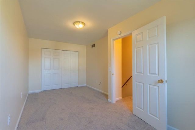 unfurnished bedroom with light colored carpet and a closet