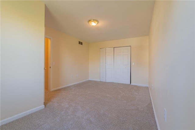 unfurnished bedroom featuring a closet and light colored carpet