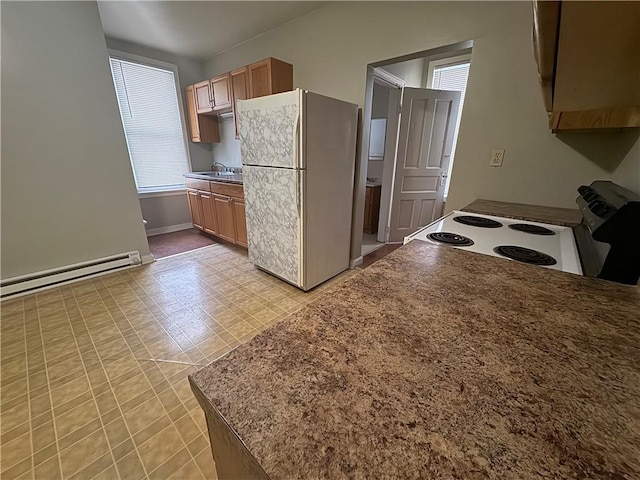 kitchen with white appliances, baseboard heating, and sink