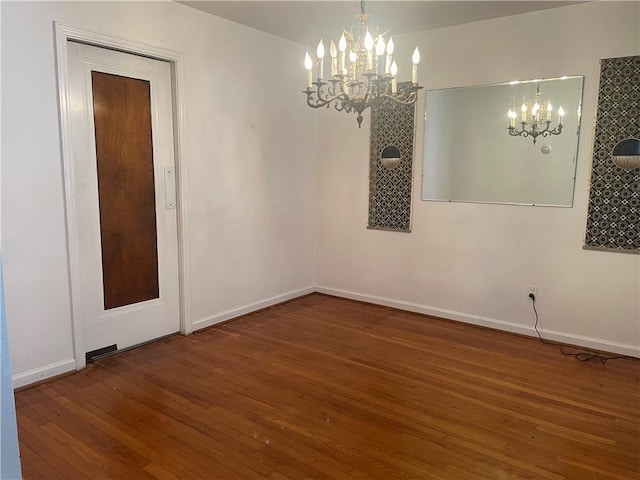 spare room featuring wood-type flooring and a chandelier