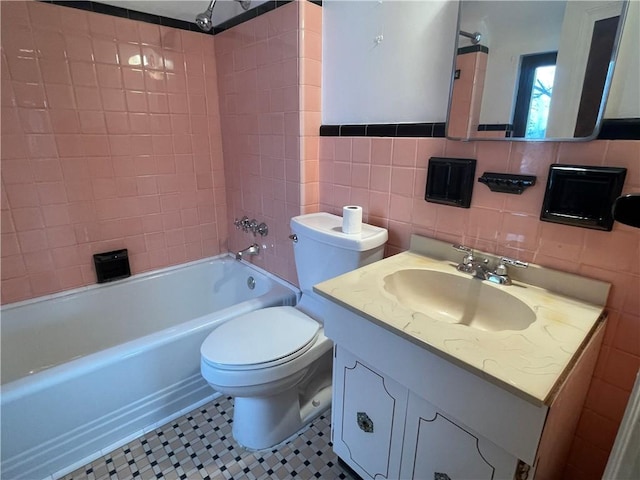 full bathroom featuring tile walls, toilet, tile patterned floors, vanity, and tiled shower / bath combo