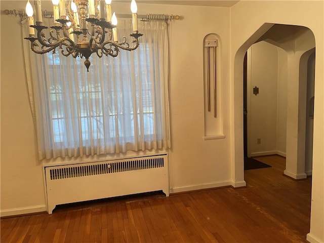 unfurnished dining area with radiator, dark hardwood / wood-style flooring, and a notable chandelier