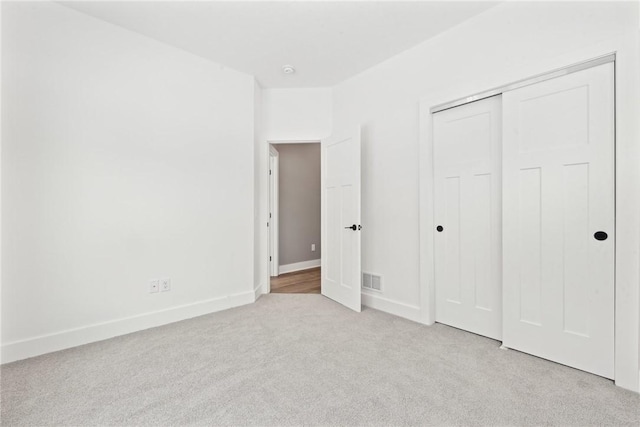 unfurnished bedroom featuring light carpet and a closet