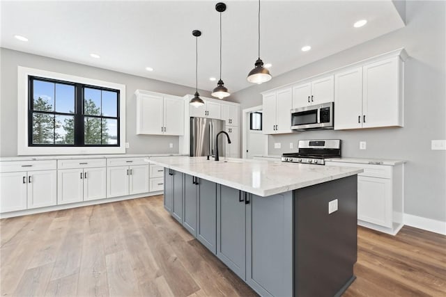 kitchen with pendant lighting, white cabinets, an island with sink, and appliances with stainless steel finishes