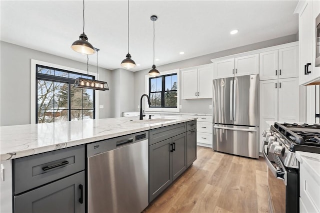 kitchen featuring appliances with stainless steel finishes, gray cabinets, white cabinetry, and hanging light fixtures