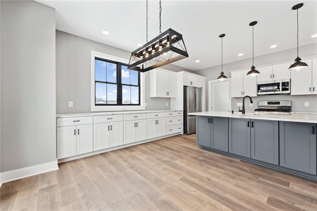 kitchen featuring gray cabinetry, white cabinets, pendant lighting, and appliances with stainless steel finishes