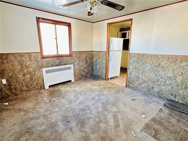 unfurnished room with light carpet, heating unit, ceiling fan, and tile walls