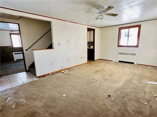 carpeted empty room featuring ceiling fan and radiator heating unit