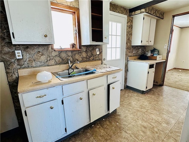 kitchen with backsplash, white cabinetry, sink, and fridge