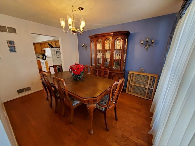 dining area with hardwood / wood-style flooring and a notable chandelier