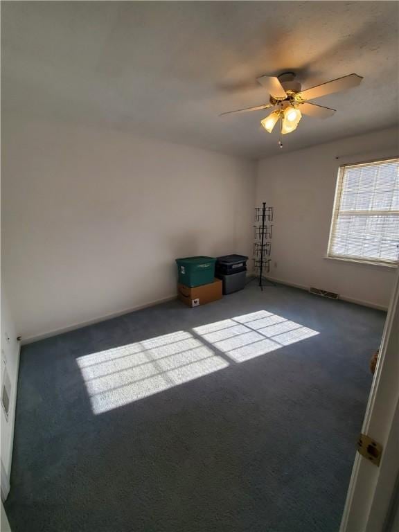 unfurnished room featuring dark colored carpet and ceiling fan